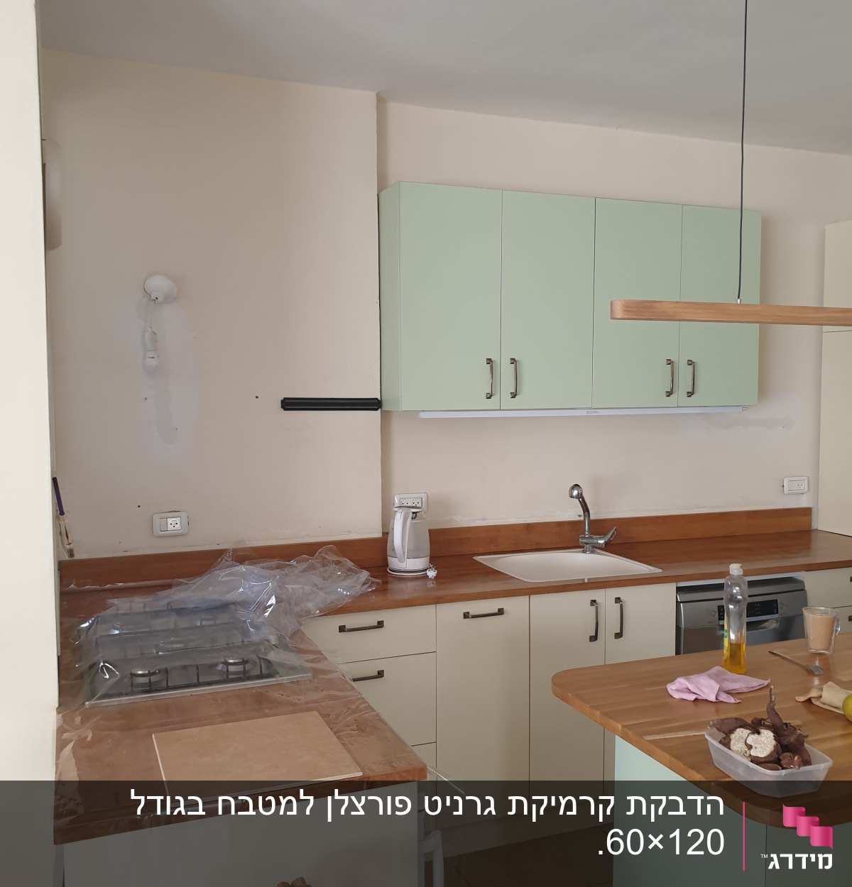 מטבח בשיפוץ עם ארונות ירוקים, כיור וברז מותקנים
